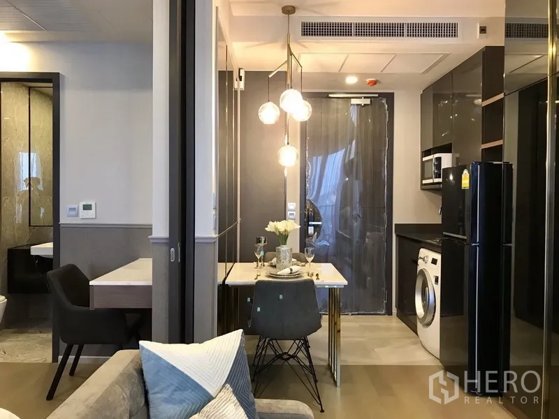 คอนโด ให้เช่าในWatthana, Bangkok - ครัวบิลท์อินตู้เงา เครื่องซักผ้า พร้อมมุมทานอาหารสองที่นั่งใต้โคมไฟแขวนในคอนโดโมเดิร์น