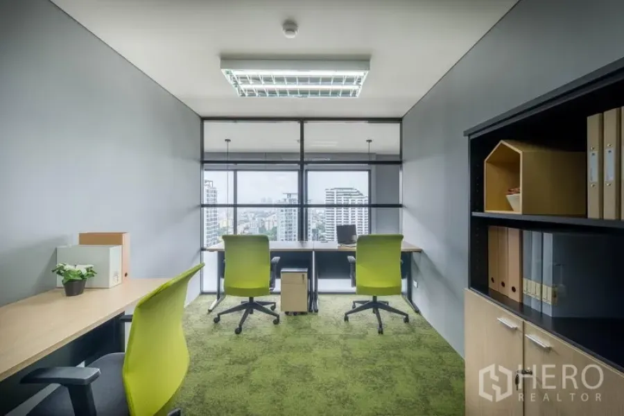 办公空间 出租在Chatuchak, Bangkok - 私密办公室，绿色地毯、书架与书桌，通过玻璃可见城市天际线。