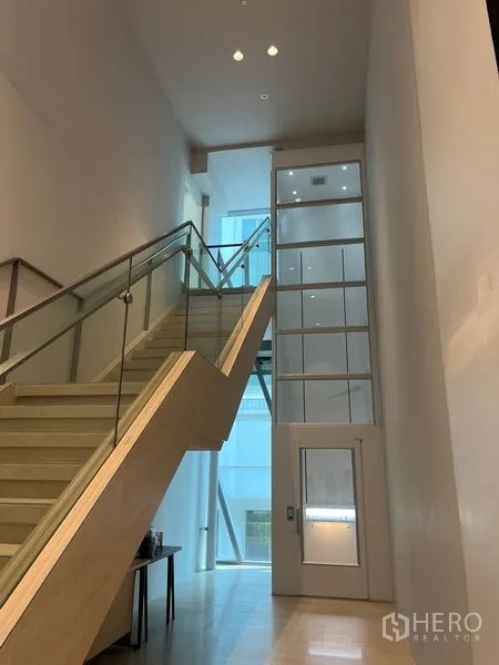 零售空间 出租在Pathum Wan, Bangkok - 现代大堂，玻璃栏杆楼梯与小型电梯相邻。