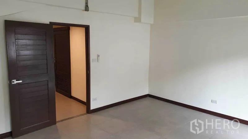 ทาวน์เฮาส์ ให้เช่าหรือขายในKhlong Toei, Bangkok - ห้องนอนกว้างพร้อมประตูไม้และพื้นกระเบื้องโทนสุภาพ