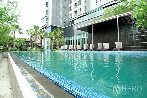 Condominium for rent in Ratchathewi, Bangkok - Outdoor lap swimming pool with sun loungers and landscaped garden at the condominium