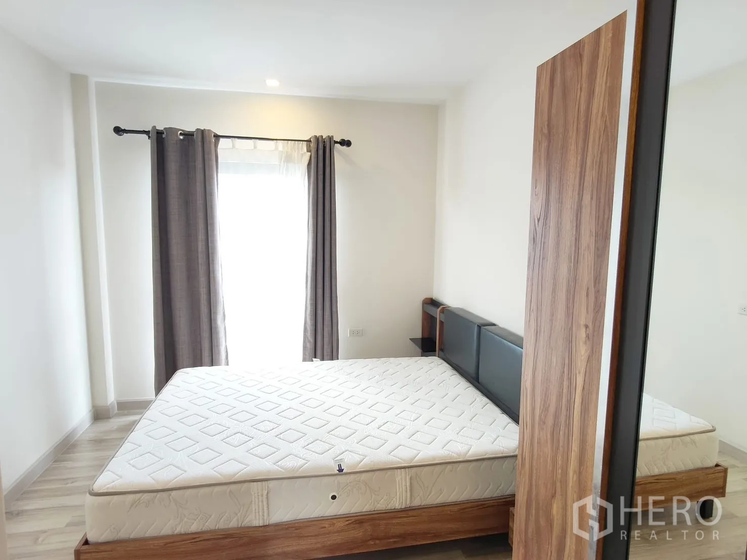 Townhouse for rent in Saphan Sung, Bangkok - Second bedroom with large bed, sliding wardrobe and floor-to-ceiling window with drapes.