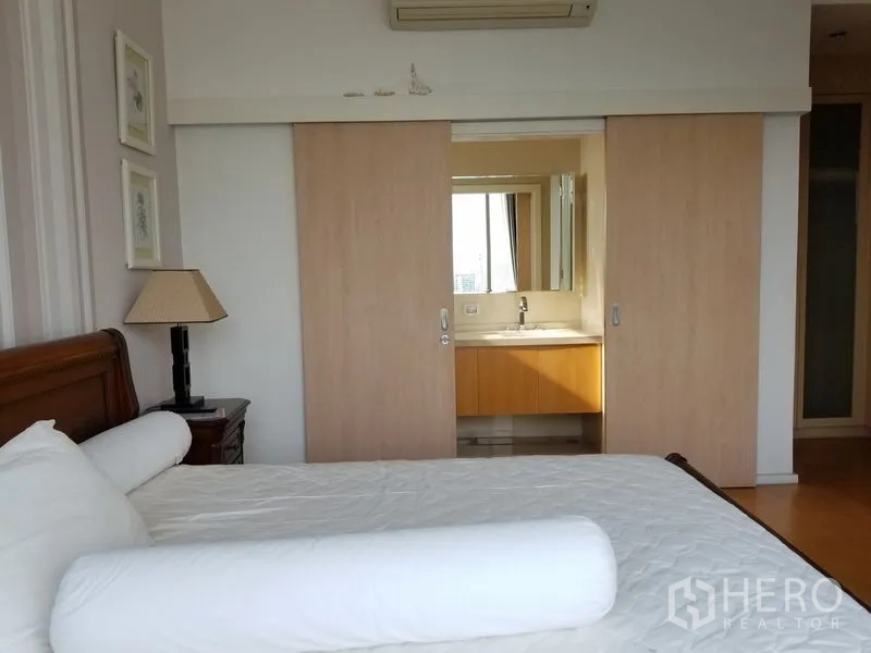 Condominium for rent in Chatuchak, Bangkok - Master bedroom leading to an en‑suite bathroom through light wood sliding doors.