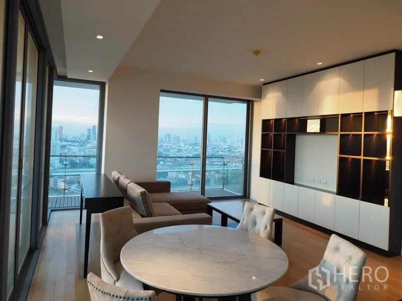 Condominium for rent in Yan Nawa, Bangkok - Corner living area with round dining table and sofa facing panoramic city and river views.