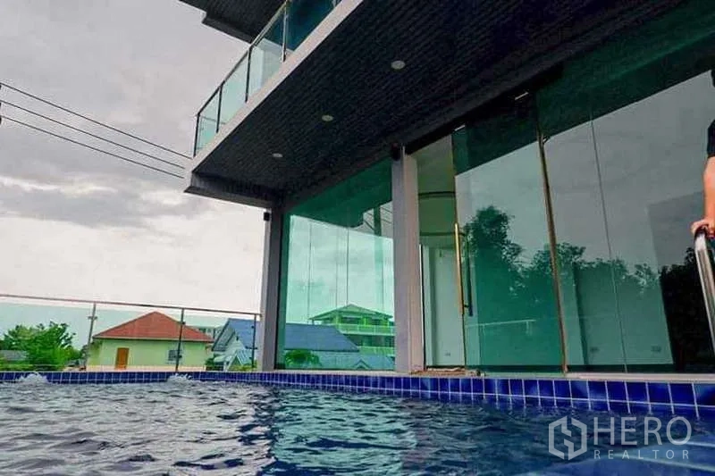 บ้าน ขายในLat Phrao, Bangkok - มุมมองระดับสระ เห็นผนังกระจกของตัวบ้านและระเบียงด้านบน