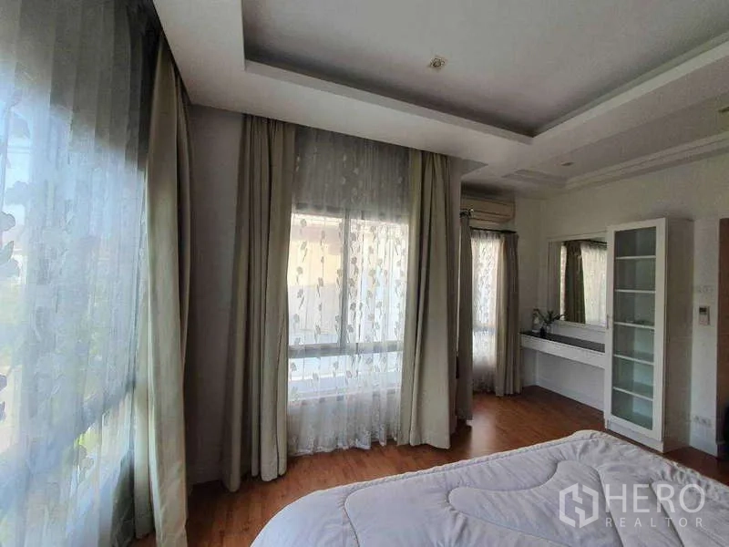 Detached House for rent in Saphan Sung, Bangkok - Master bedroom corner with sheer curtains, wide windows and a vanity.