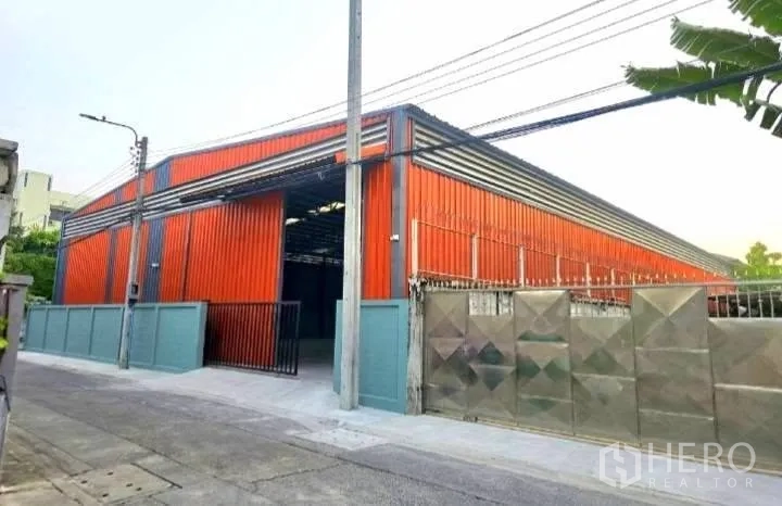 Warehouse for rent in Phaya Thai, Bangkok - Street-side view of the warehouse showing a gated entrance, perimeter wall, and wide access.