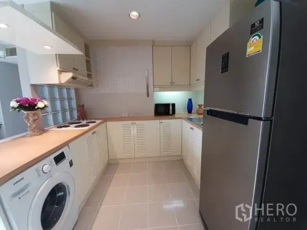 公寓 出租或出售在Watthana, Bangkok - U形厨房配大号不锈钢冰箱、洗衣机和瓷砖地面。