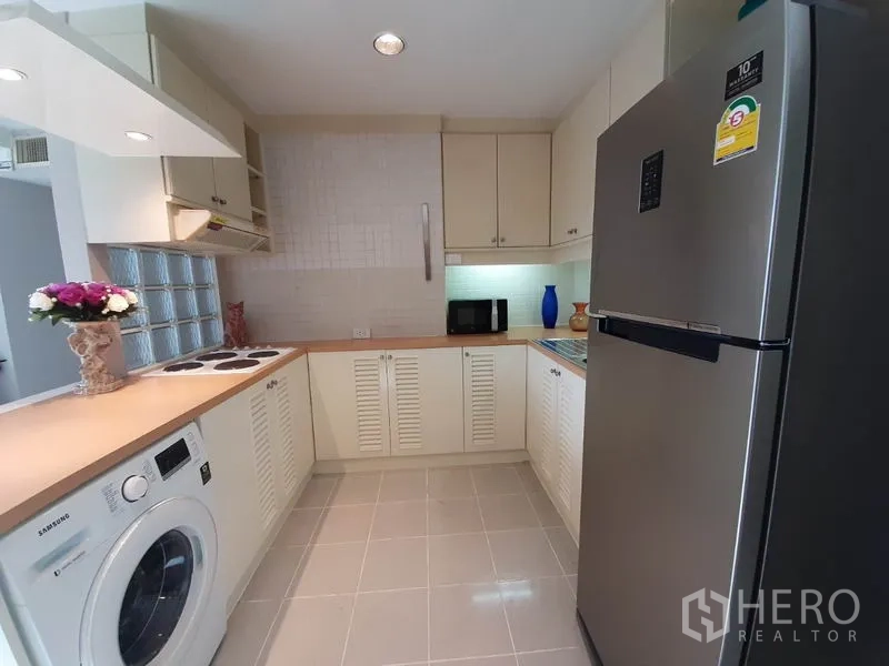 公寓 出租或出售在Watthana, Bangkok - U形厨房配大号不锈钢冰箱、洗衣机和瓷砖地面。