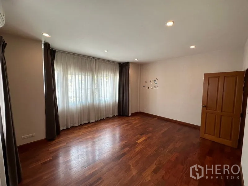 Detached House for rent or sale in Pak Kret, Nonthaburi - Secondary bedroom with wide corner windows and wooden flooring.