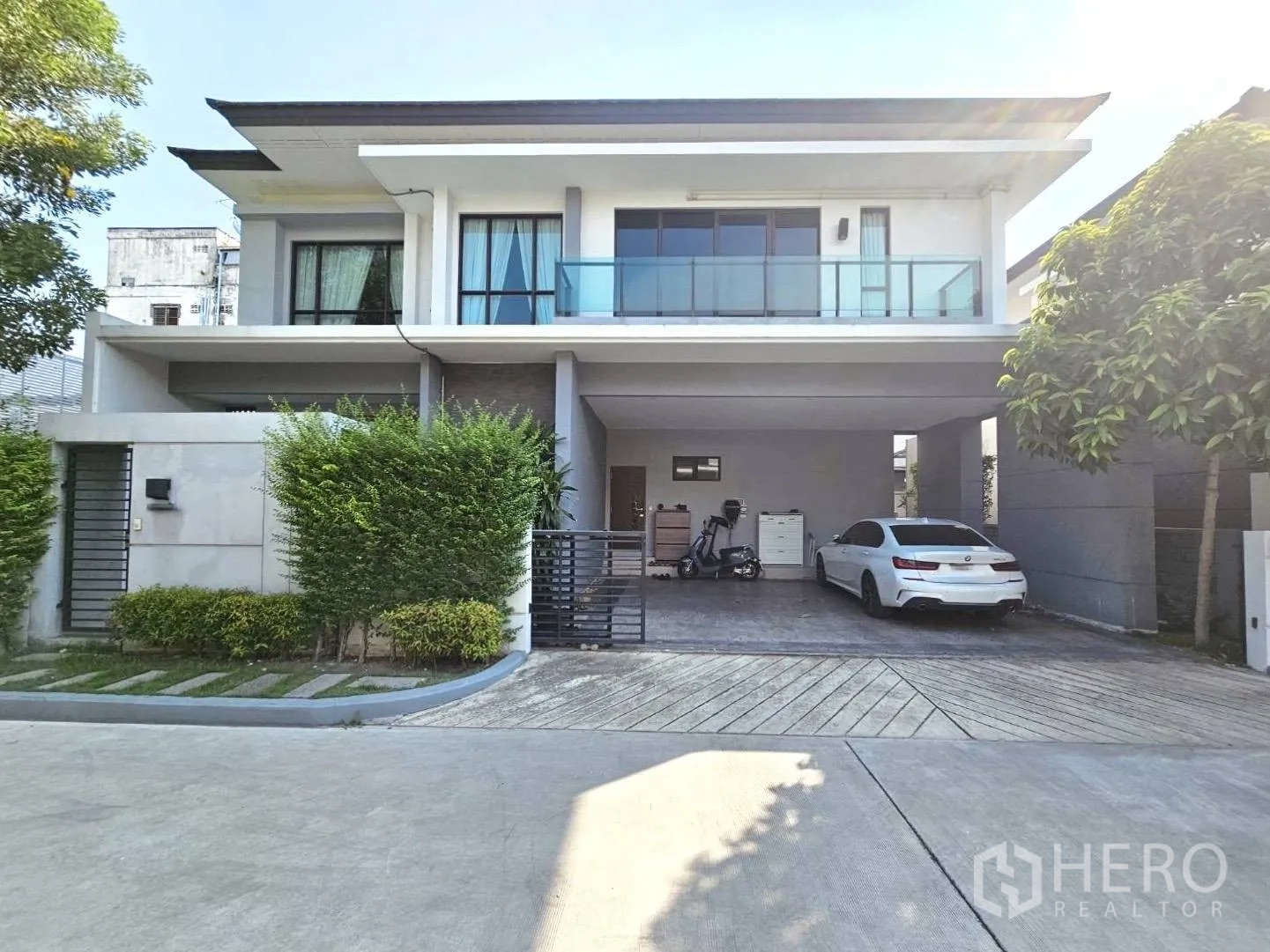 Detached House for rent in Wang Thonglang, Bangkok - Contemporary two-storey house with gated entrance, covered double carport, balcony, and driveway.