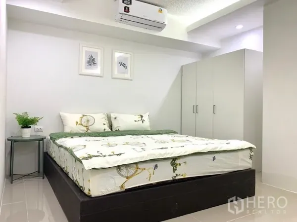 คอนโด ให้เช่าหรือขายในKhlong Toei, Bangkok - ห้องนอนติดแอร์ เตียงคู่ ตู้เสื้อผ้าสีขาว และโต๊ะข้าง เต็มไปด้วยโทนสีอบอุ่น