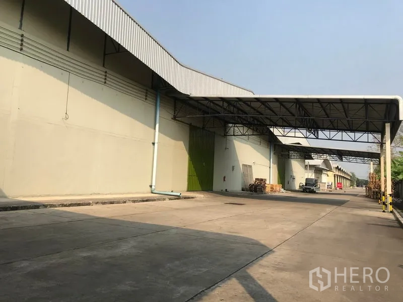 货栈 出租在Bang Pa-in, Phra Nakhon Si Ayutthaya - 仓库外观，带有雨棚装卸区与宽阔混凝土车道，可容卡车通行