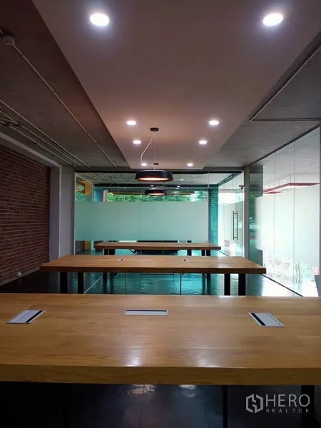 办公空间 出租在Khlong Toei, Bangkok - 共享木质工位排布，圆形吊灯下的玻璃隔间。