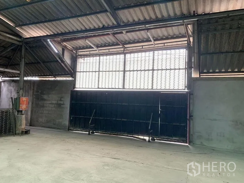 Warehouse for rent - Wide sliding metal gate with glass-block clerestory inside a high-roof warehouse.