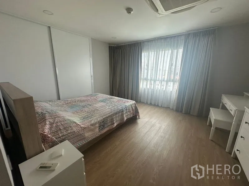 Condominium for rent - Spacious bedroom with large window, sheer curtains, wood floors and a queen bed.
