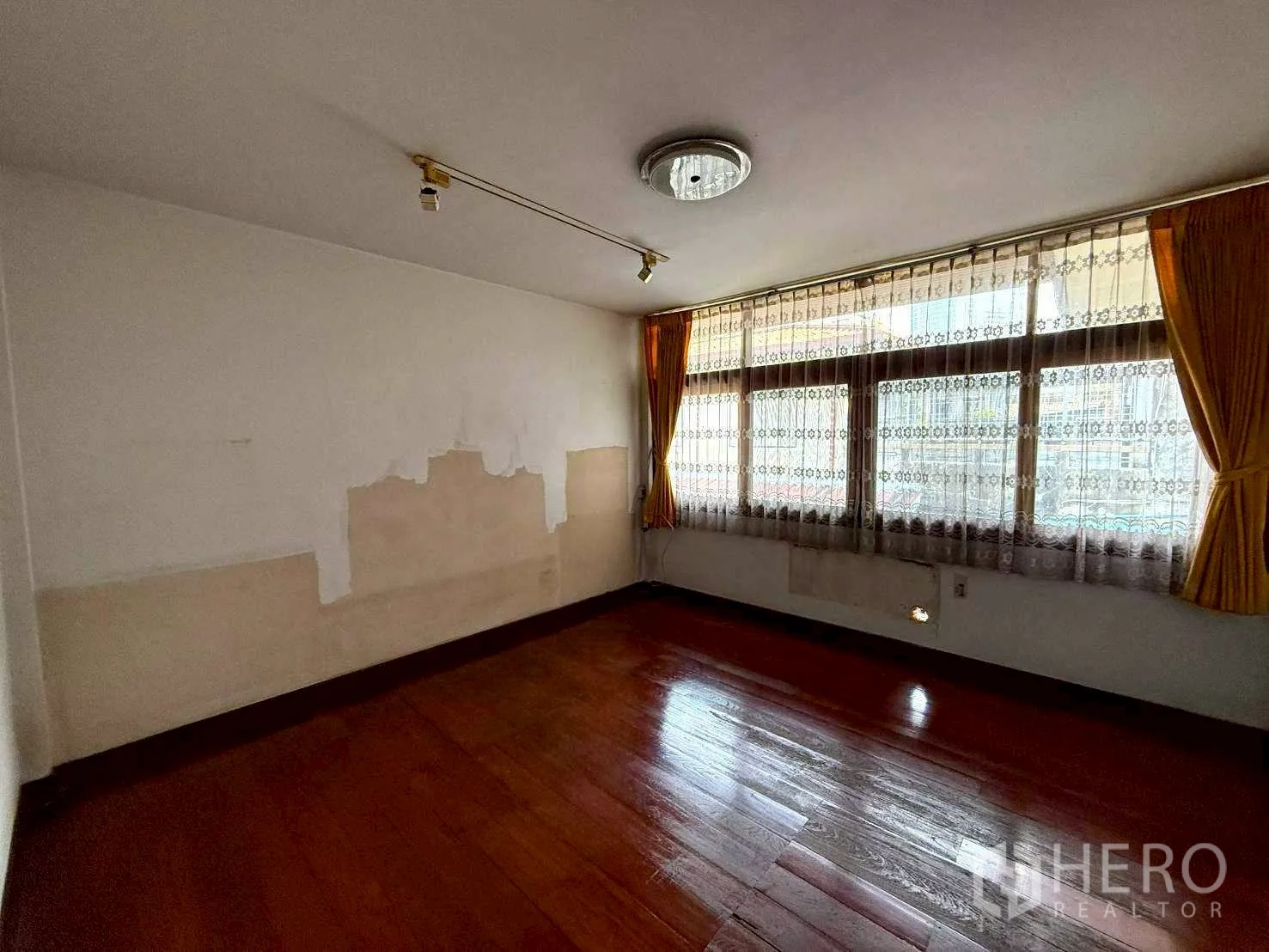Home Office for rent in Bang Rak, Bangkok - Bright room with large curtained windows and polished wooden flooring.
