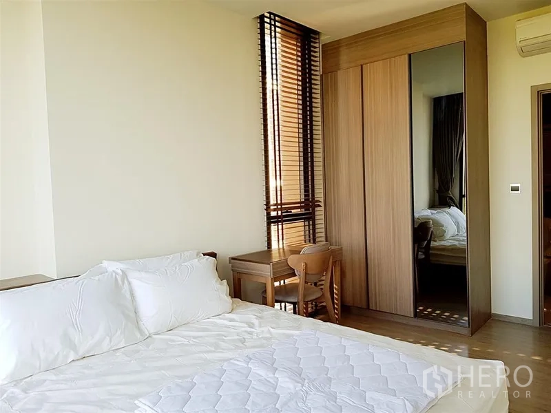 Condominium for rent in Watthana, Bangkok - Master bedroom showing wardrobe, desk, and slim window blinds.