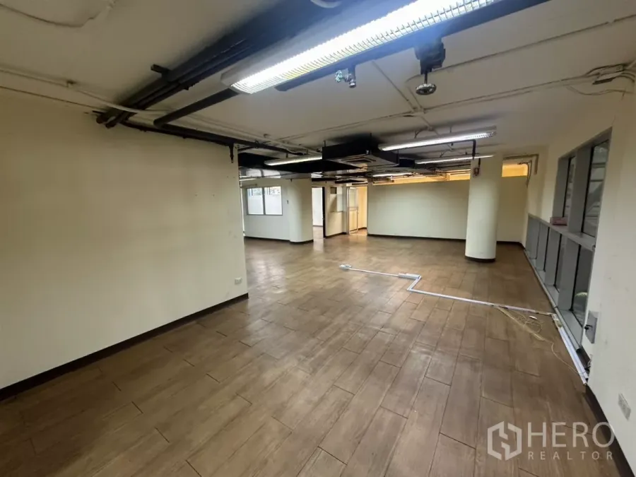 คลังสินค้า ให้เช่า - พื้นที่เปิดโล่งปรับอากาศ พื้นกระเบื้องลายไม้ เพดานเปลือย โคมไฟและเสาโครงอาคาร