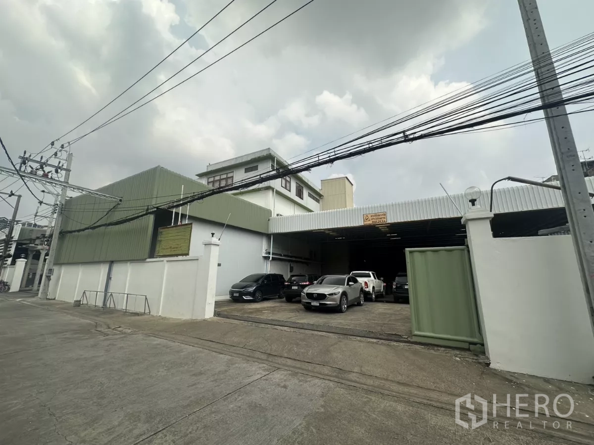 คลังสินค้า ให้เช่าในYan Nawa, Bangkok - มุมมองจากถนนของโกดังยานนาวาพร้อมรั้วและผนังเมทัลชีทสีเขียว มีที่จอดรถด้านหน้า