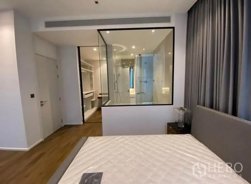 Condominium for rent in Pathum Wan, Bangkok - Primary suite showing glass-walled en-suite bathroom and walk-in closet viewed from the bed.