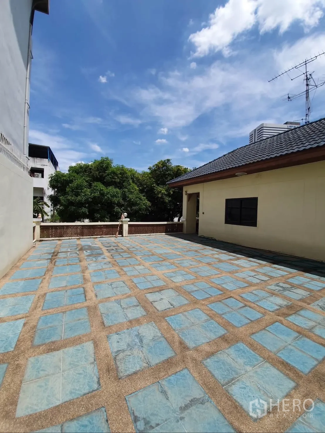 Detached House for rent in Sathon, Bangkok - Large open tiled terrace beside the house under a blue sky.