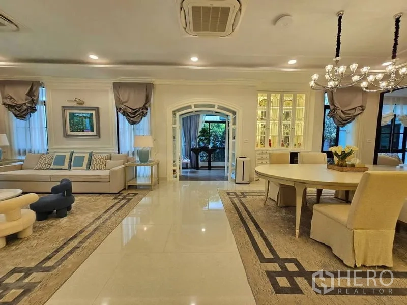 Detached House for rent or sale in Saphan Sung, Bangkok - Open-plan living and dining area with feature lighting, sofas and display cabinets.