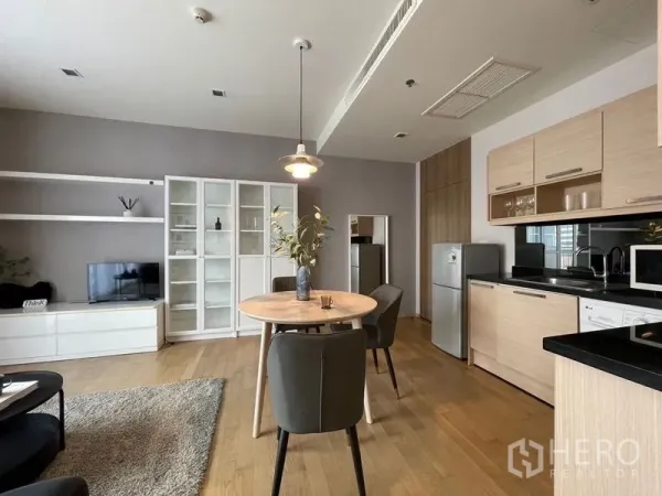 คอนโด ให้เช่าในWatthana, Bangkok - ครัวสมัยใหม่ตู้ไม้โทนอ่อนข้างโต๊ะอาหาร และชั้นทีวีในห้องนั่งเล่นโปร่ง