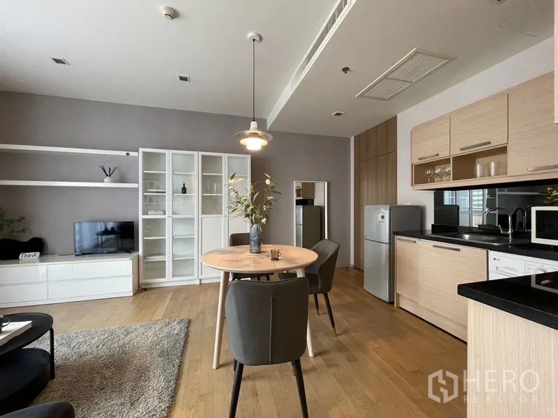 คอนโด ให้เช่าในWatthana, Bangkok - ครัวสมัยใหม่ตู้ไม้โทนอ่อนข้างโต๊ะอาหาร และชั้นทีวีในห้องนั่งเล่นโปร่ง