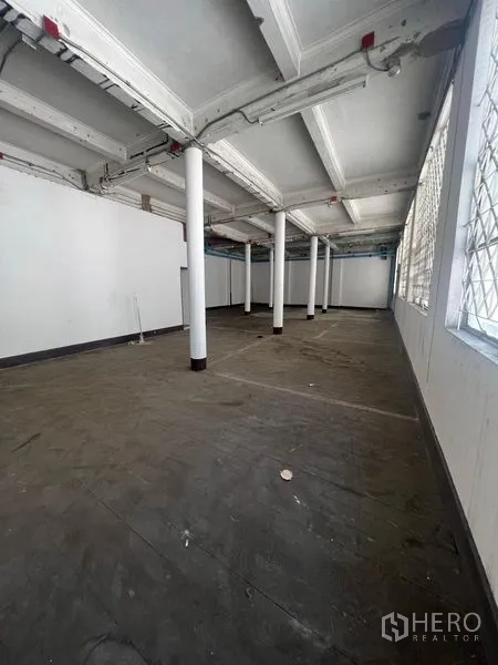 Shophouse for rent in Samphanthawong, Bangkok - Long open-plan level with high windows and structural columns.