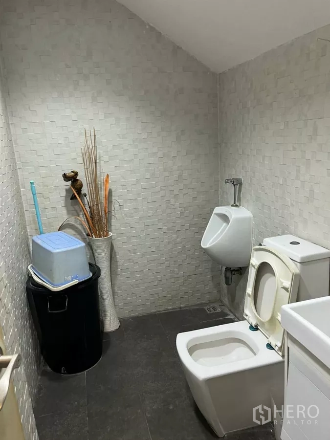 Home Office for rent in Khlong Toei, Bangkok - Restroom with toilet, urinal and textured wall tiles.