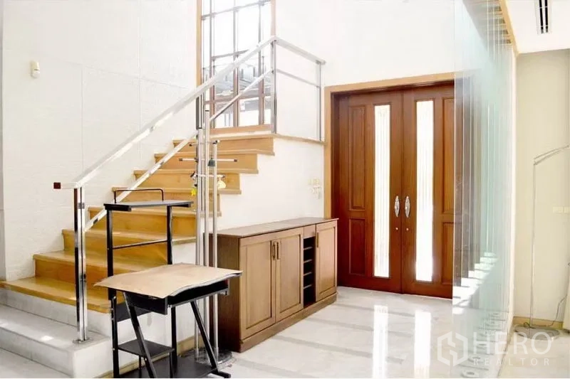 Detached House for rent or sale in Bang Phli, Samut Prakan - Entrance hall with wooden double doors and a staircase with stainless‑steel railing.