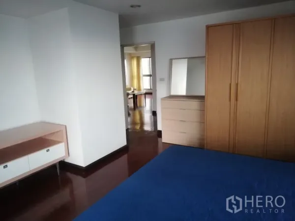 คอนโด ให้เช่าในPhaya Thai, Bangkok - ห้องนอนหลักพร้อมผ้าปูเตียงสีน้ำเงิน ตู้เสื้อไม้ และพื้นไม้ขัดมันวาวต่อเนื่องไปยังโซนรับแขก