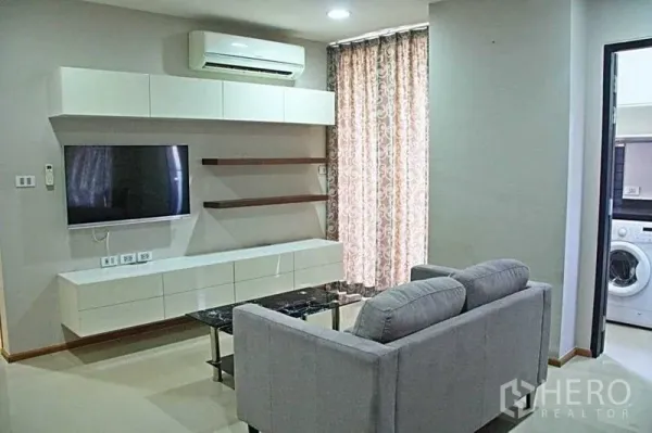 คอนโด ให้เช่าในPhaya Thai, Bangkok - พื้นที่นั่งเล่นพร้อมชั้นวางทีวีติดผนัง เครื่องปรับอากาศ และประตูเข้าครัวมีเครื่องซักผ้า