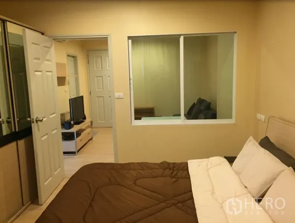 Condominium for rent in Bang Rak, Bangkok - Bedroom view showing wardrobe, interior window to the living room and wooden flooring.