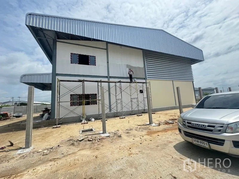 คลังสินค้า ให้เช่าในMueang Samut Prakan, Samut Prakan - ด้านข้างอาคารโกดังสร้างใหม่ ผนังเมทัลชีทและลานโล่งใต้ท้องฟ้ามีเมฆ