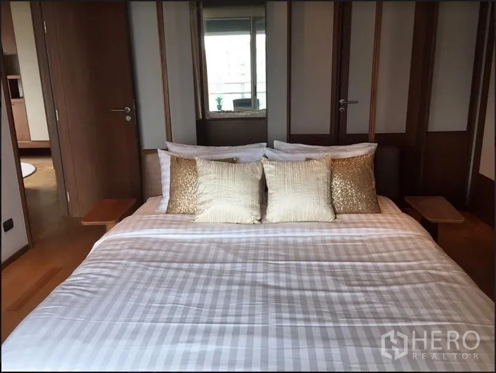 Condominium for rent in Watthana, Bangkok - Primary bedroom with upholstered bed, wood accents and wardrobes.