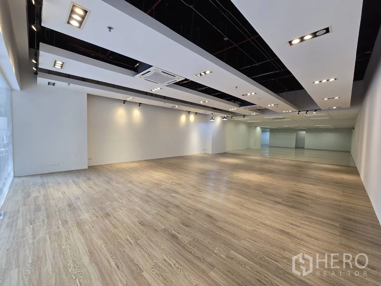 Retail Space for rent in Watthana, Bangkok - Spacious showroom with wood-look flooring and track spotlights.
