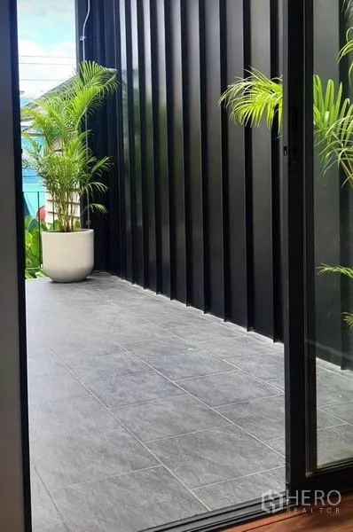 Home Office for rent or sale in Khlong Toei, Bangkok - Covered terrace with dark cladding and gray tiles featuring potted palms near the railing.