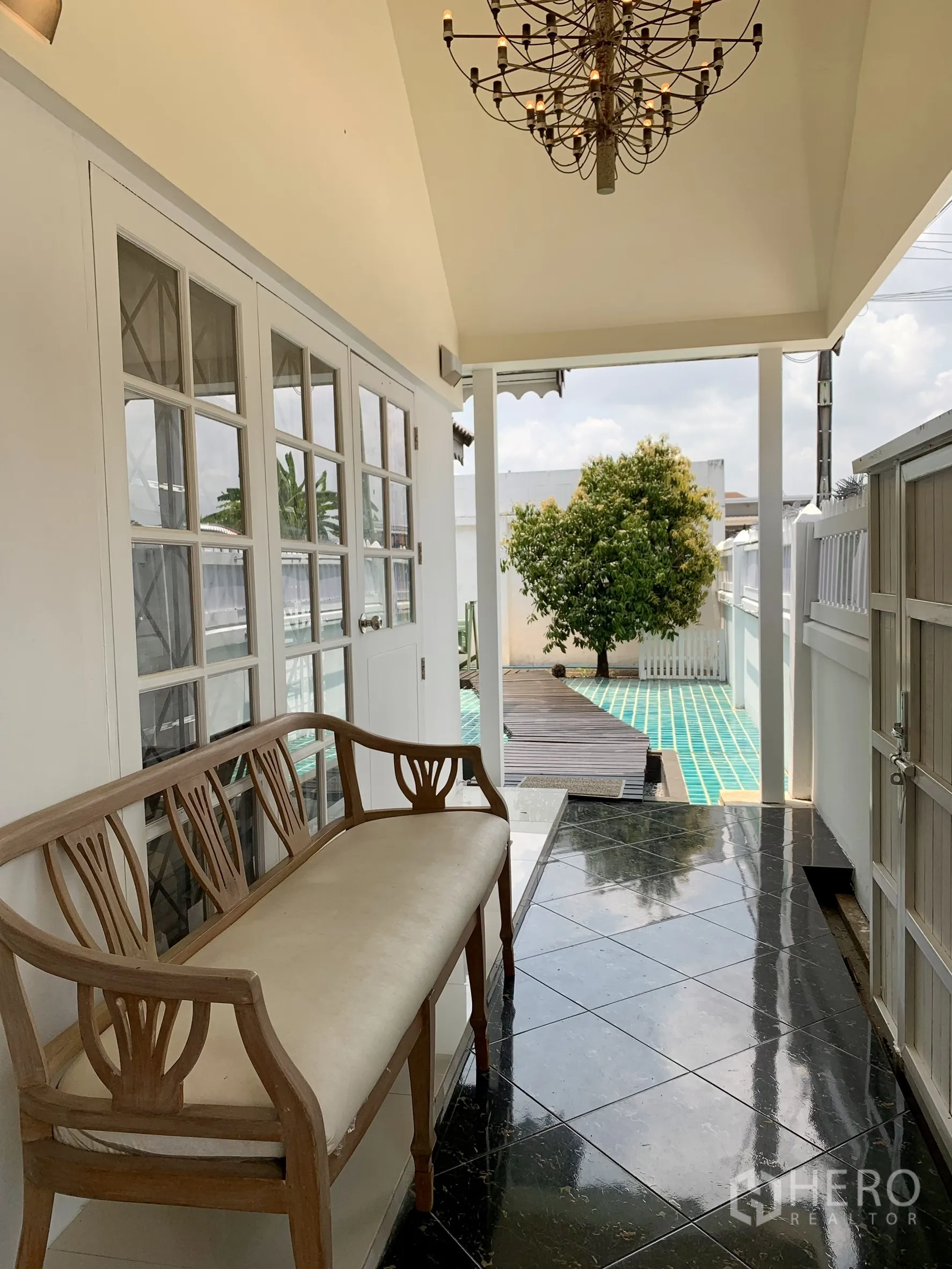 บ้านเดี่ยว for rent in Saphan Sung, Bangkok - โถงชานบ้านที่มีม้านั่งและโคมไฟ เชื่อมไปยังเฉลียงกระเบื้องสีฟ้า.