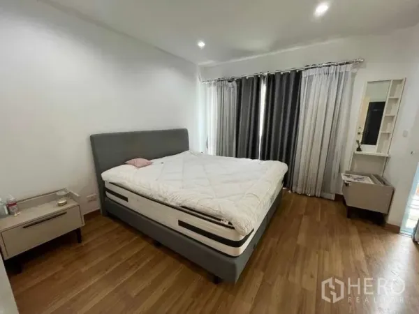 ทาวน์เฮาส์ ให้เช่าในSuan Luang, Bangkok - ห้องนอนใหญ่เตียงคิงไซส์ โต๊ะข้างเตียง และผ้าม่านทึบ