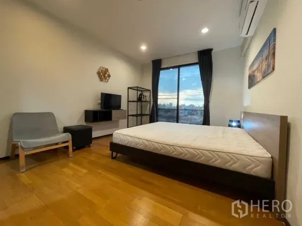 Condominium for rent in Din Daeng, Bangkok - Master bedroom with large window and balcony city view, air conditioning and minimalist decor.