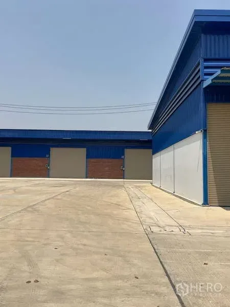 Warehouse for rent in Bang Bua Thong, Nonthaburi - Corner view of warehouse blocks with blue metal cladding and a spacious truck turning yard.