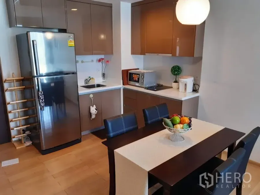 คอนโด ให้เช่าในKhlong Toei, Bangkok - ครัวรูปตัวแอลพร้อมตู้บิวท์อินเงางาม ตู้เย็นสแตนเลส ไมโครเวฟ และโต๊ะทานอาหาร 4 ที่นั่ง ในคอนโด 1 ห้องนอนย่านสุขุมวิท