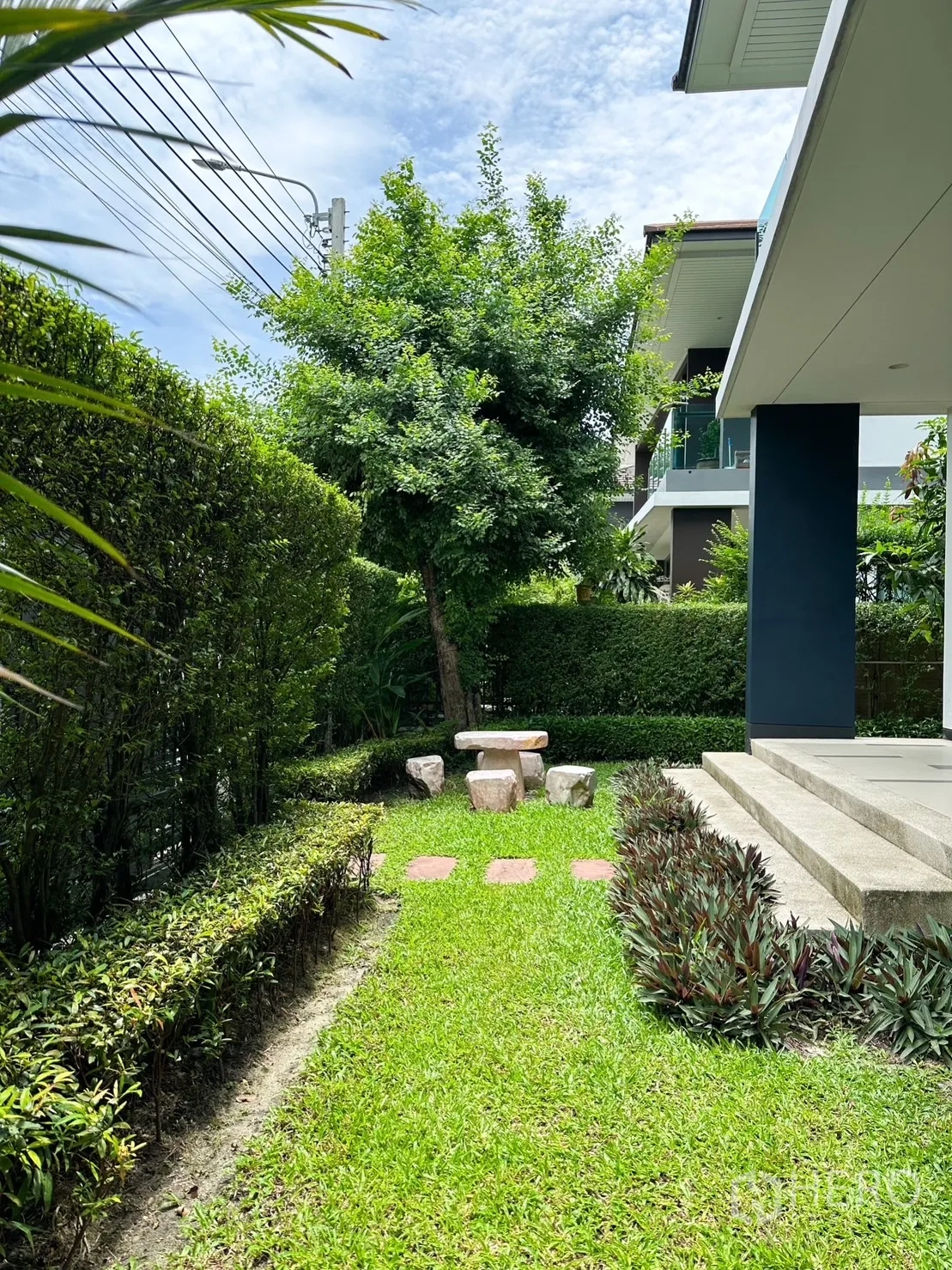 Detached House for rent or sale in Bang Kapi, Bangkok - Green lawn bordered by trimmed hedges with a stone table set beside the front patio.