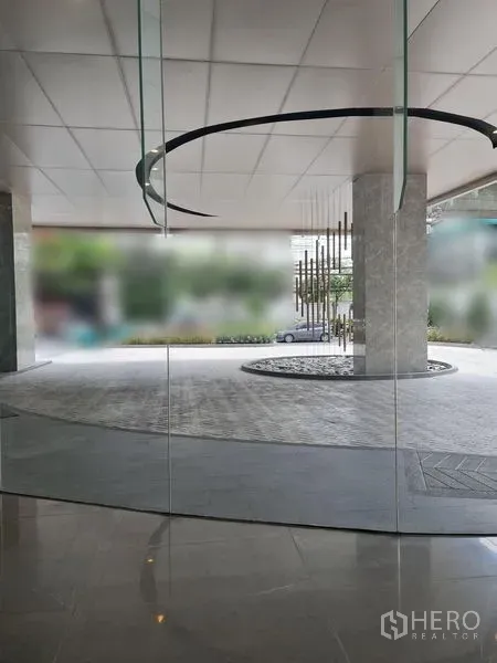 พื้นที่ขายปลีก ให้เช่า - มุมมองจากภายในผ่านผนังกระจก เห็นฝ้าเพดานลายวงกลมและงานประติมากรรม