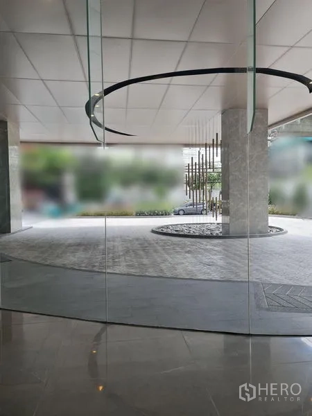 พื้นที่ขายปลีก ให้เช่า - มุมมองจากภายในผ่านผนังกระจก เห็นฝ้าเพดานลายวงกลมและงานประติมากรรม