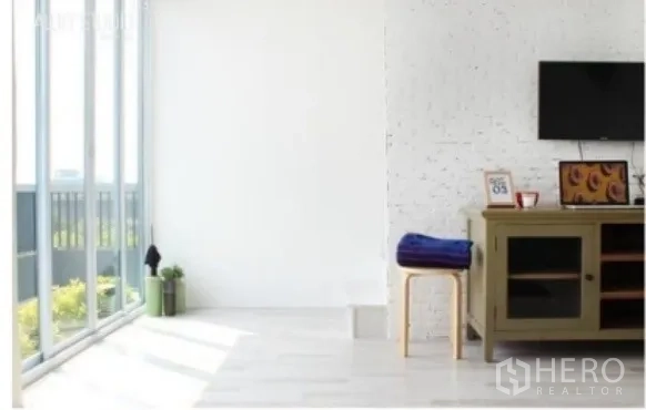 公寓 出售在Phra Khanong, Bangkok - 落地窗旁的电视角，矮柜与小凳，光线充足。