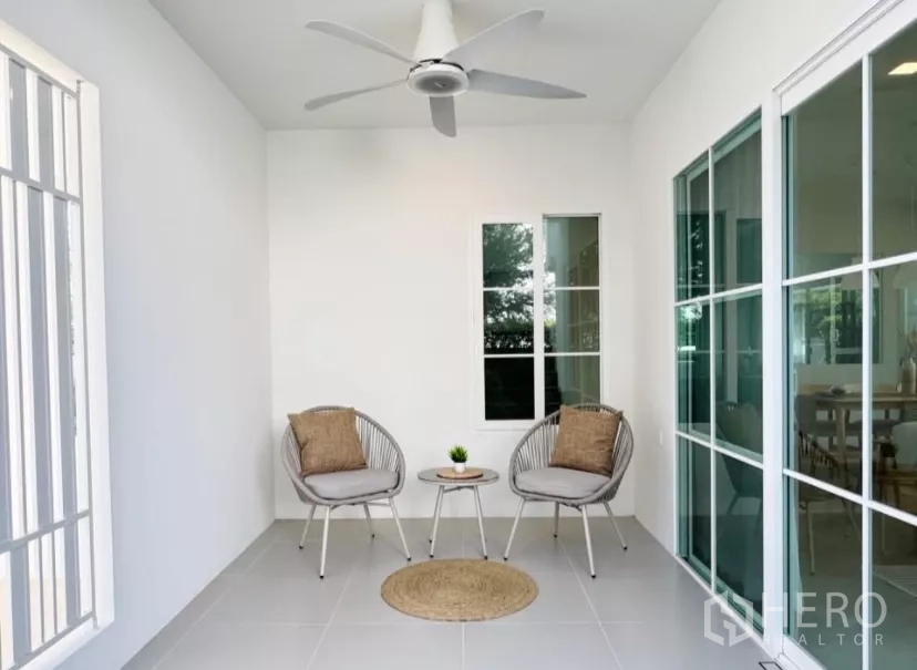 บ้าน ให้เช่าในBang Phli, Samut Prakan - เฉลียงนั่งเล่นในร่มพร้อมพัดลมเพดานและเก้าอี้พักผ่อนสองตัว