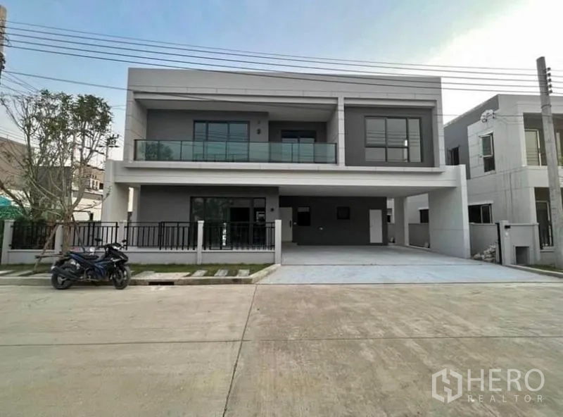 Detached House for rent in Bang Phli, Samut Prakan - Modern two-storey detached house in Bang Phli with glass balcony, gated fence and a wide double carport.
